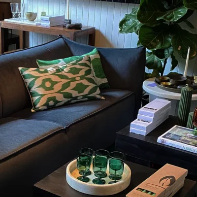 a display of furniture, glassware, books, trays and candles set up like a room. a link to our curated homewares department